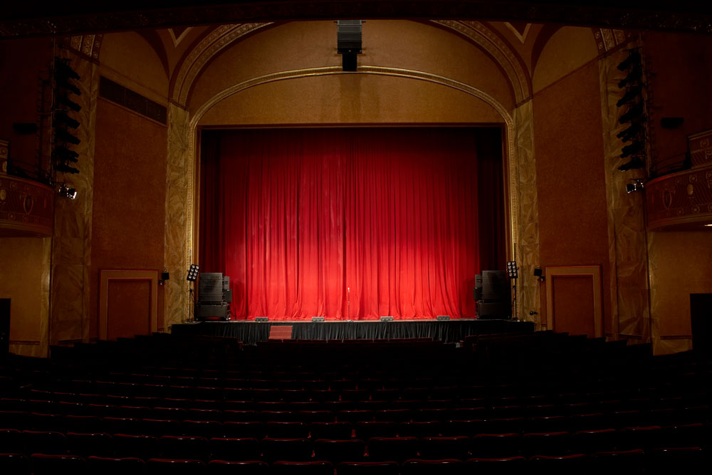 Empty theatre with stage and red curtain.